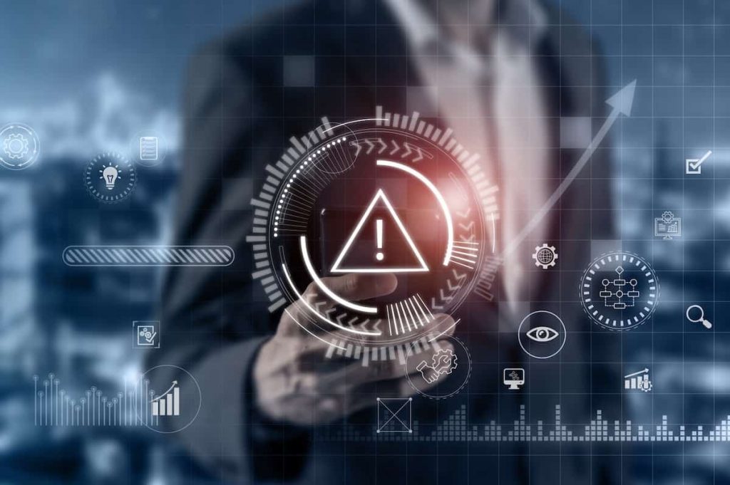 Incidence response 4 » admin by request Businessman interacting with a digital interface displaying a warning symbol and advanced analytics for risk management.